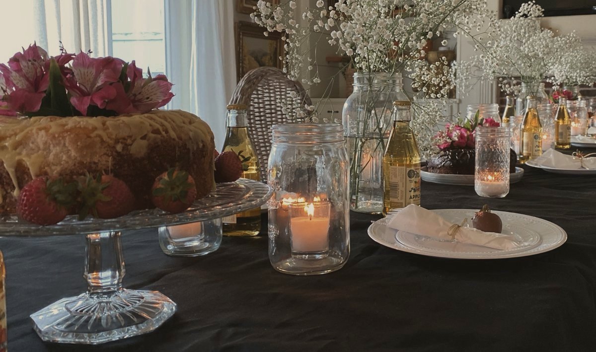 A long table with a black tablecloth, mason jar candles and baby’s breath