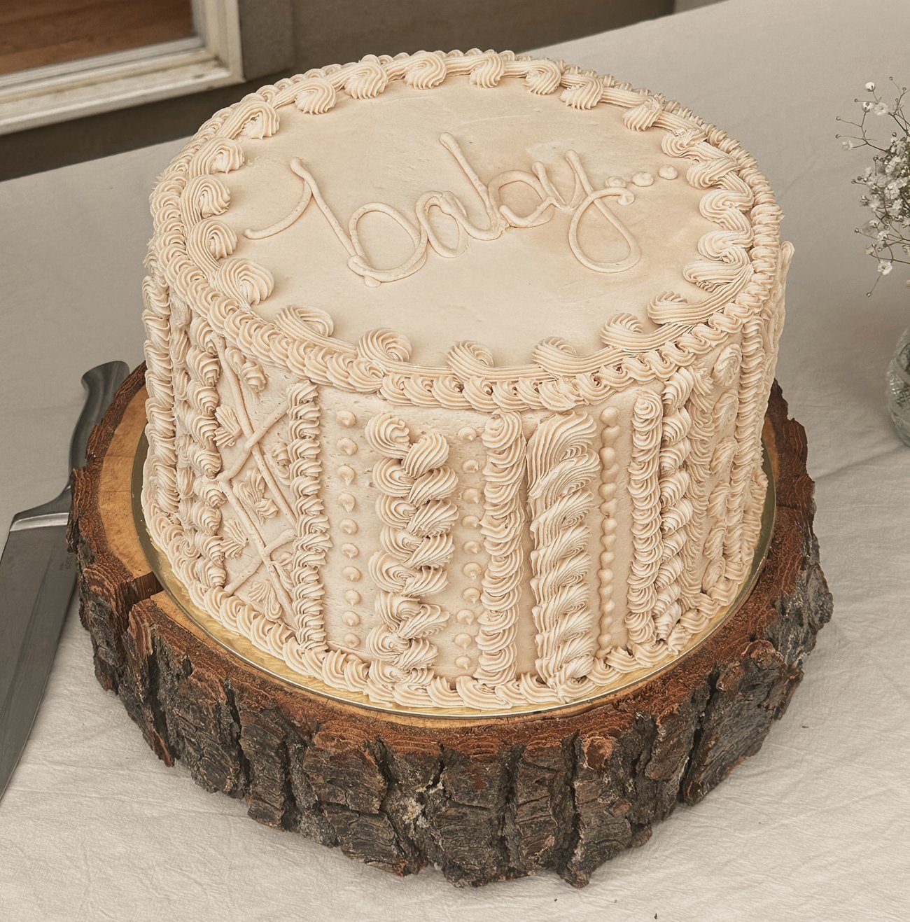 A blush cake with cable-knit piping on a wood round