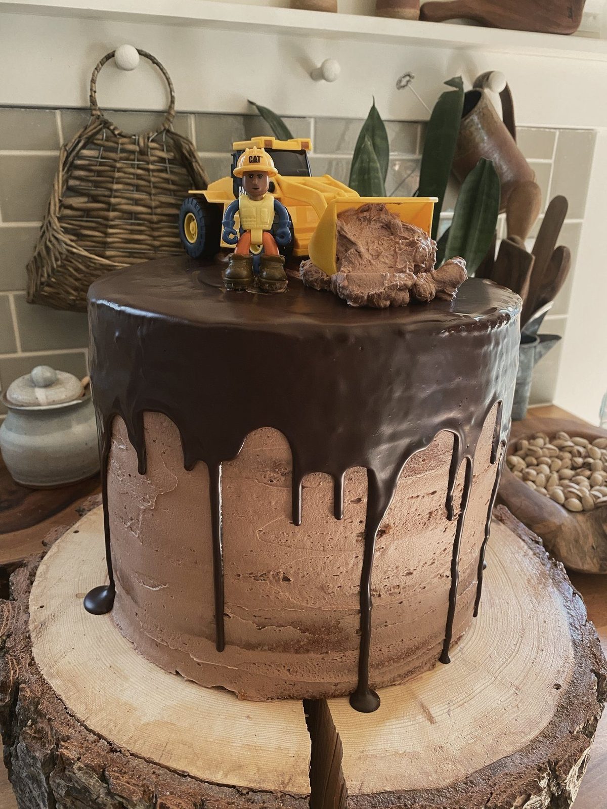 A chocolate drip cake with a toy loader on top