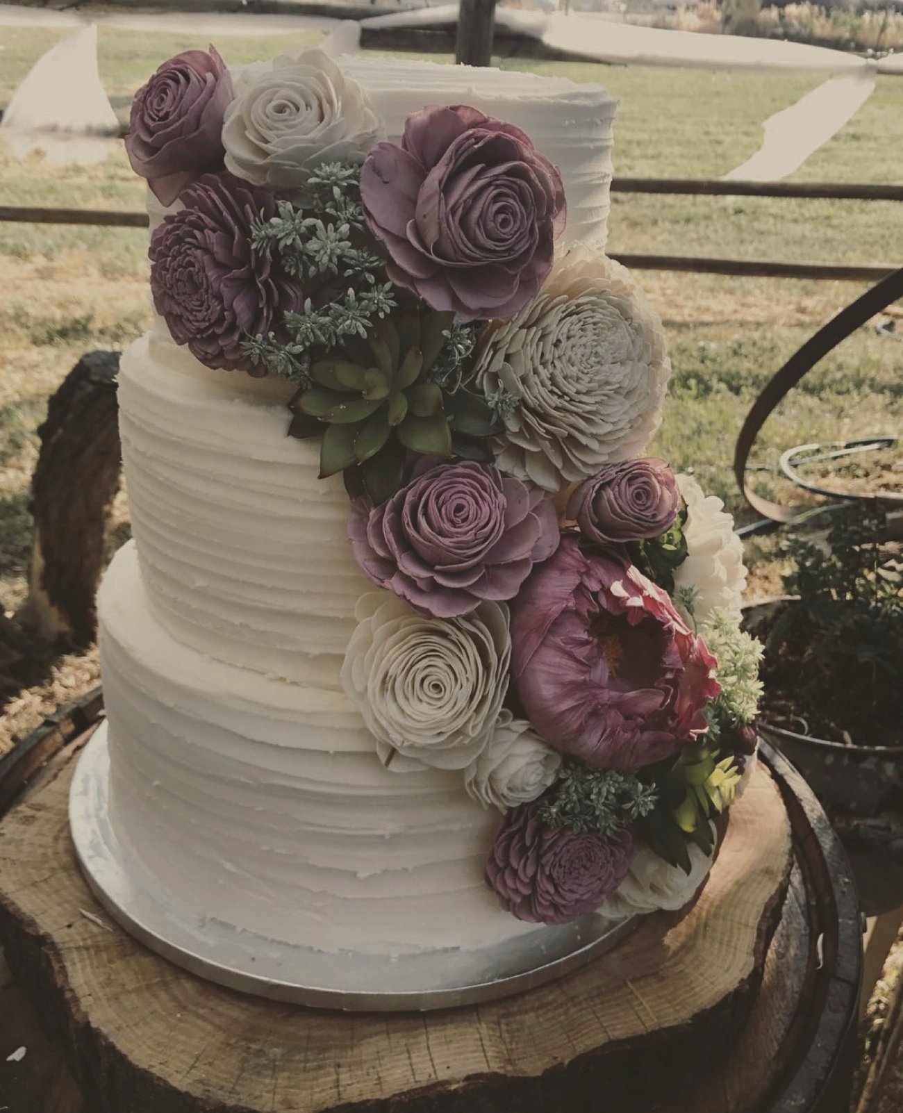 A two-tier cake with mauve wooden sola flowers