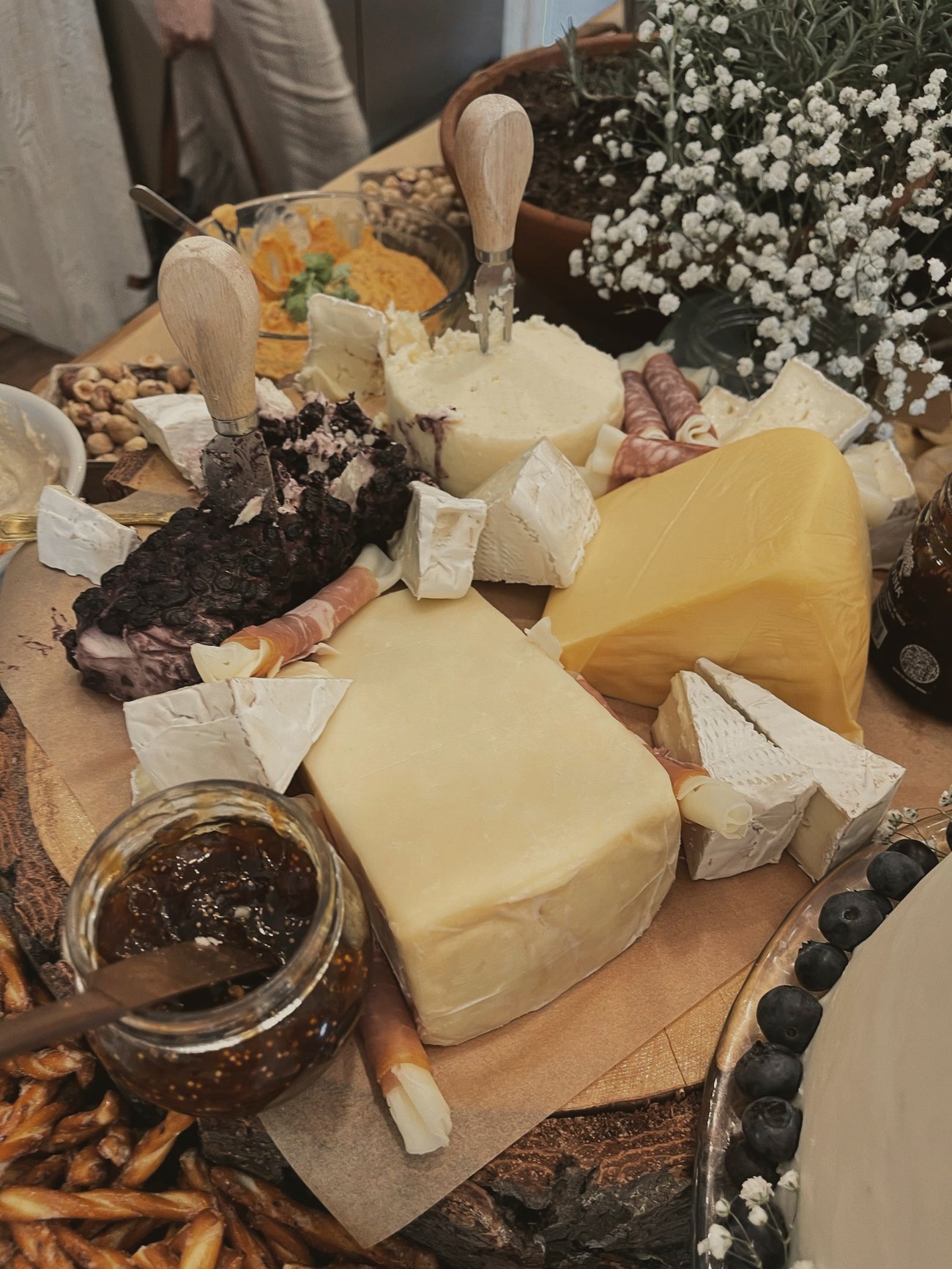 A wood round charcuterie board with cheese knives