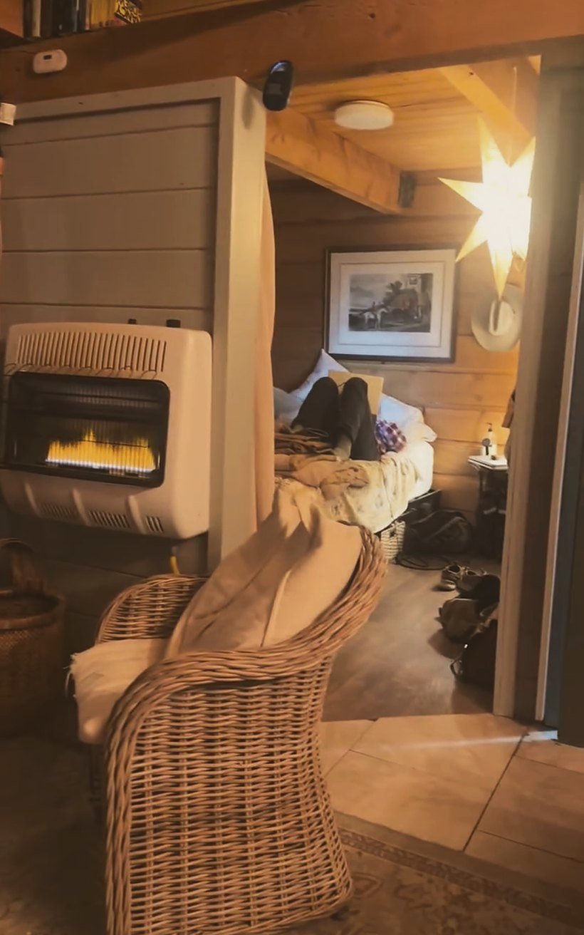 A wicker chair by the fire in the tiny cabin