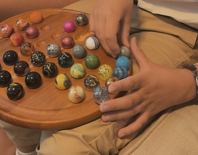 Hands moving marbles on a wooden game board