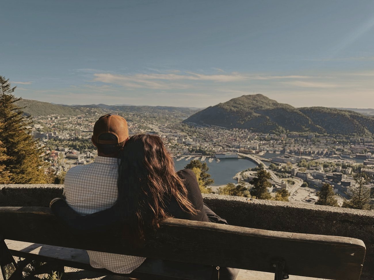 Rachel and Beau from behind on a bench above a harbor city