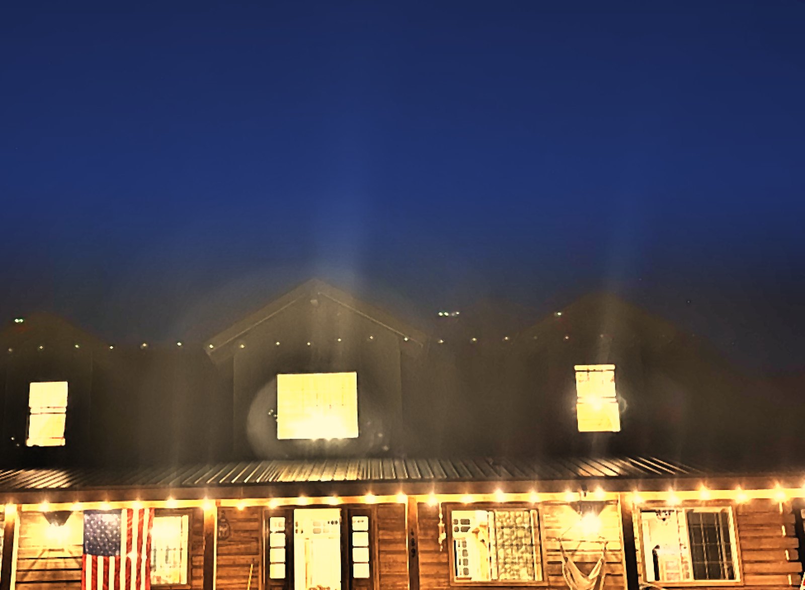Our finished log home at night, porch lights glowing