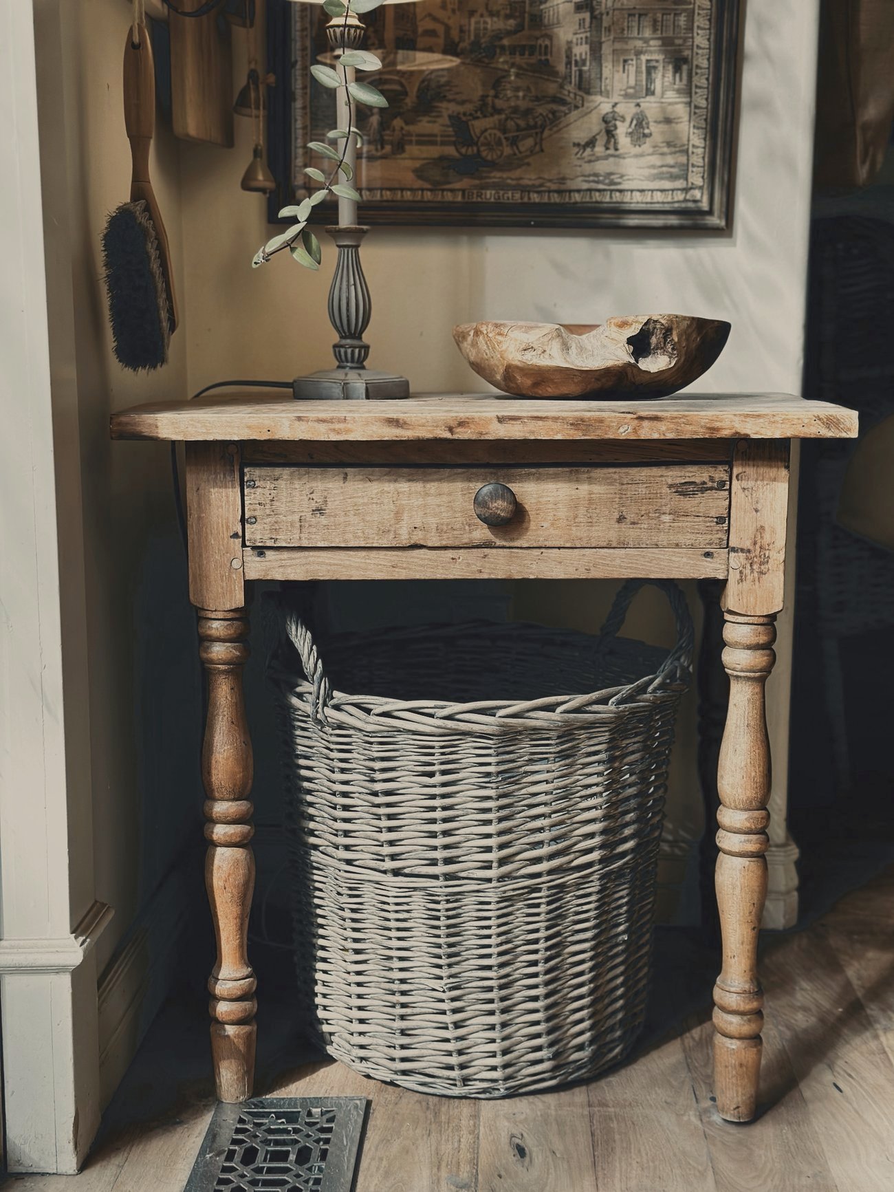 An antique pine side table with a willow basket