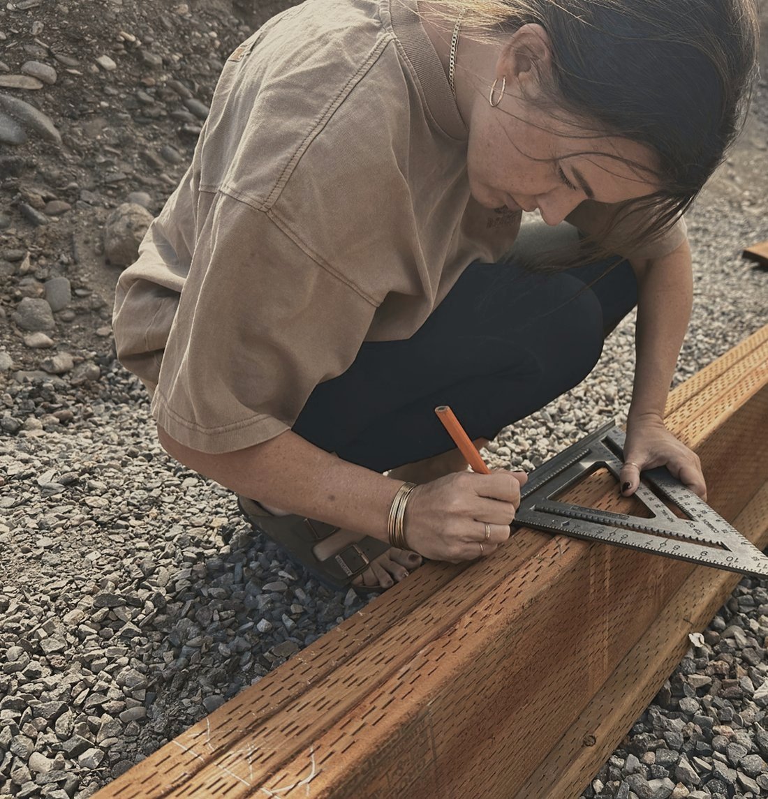 Rachel marking a beam with a carpenter pencil and speed square