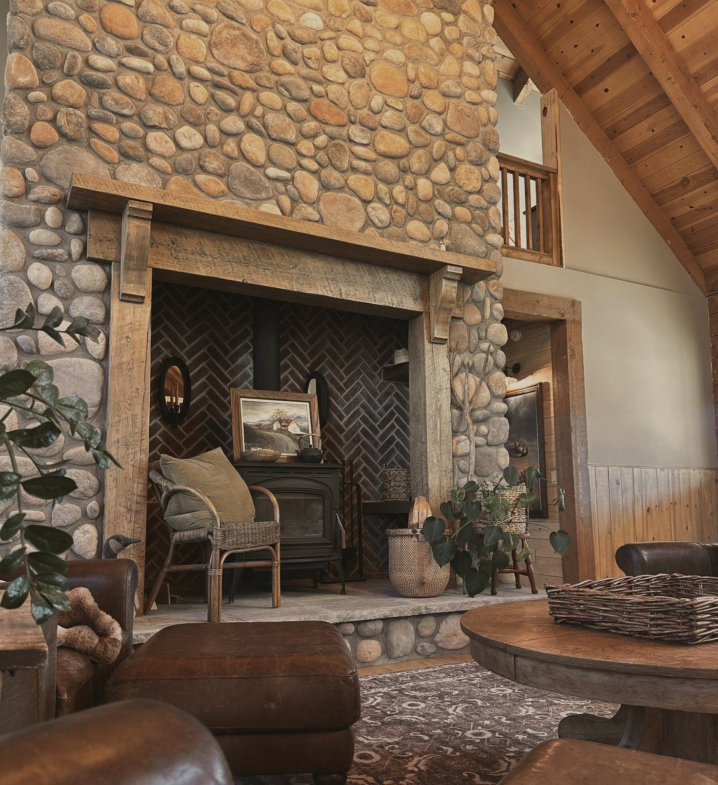Our river rock fireplace with a herringbone brick alcove, a beam mantel and leather chairs