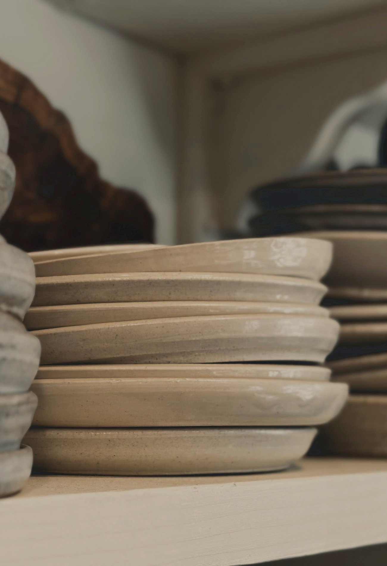 Stacked handmade speckled stoneware plates and an olive wood board