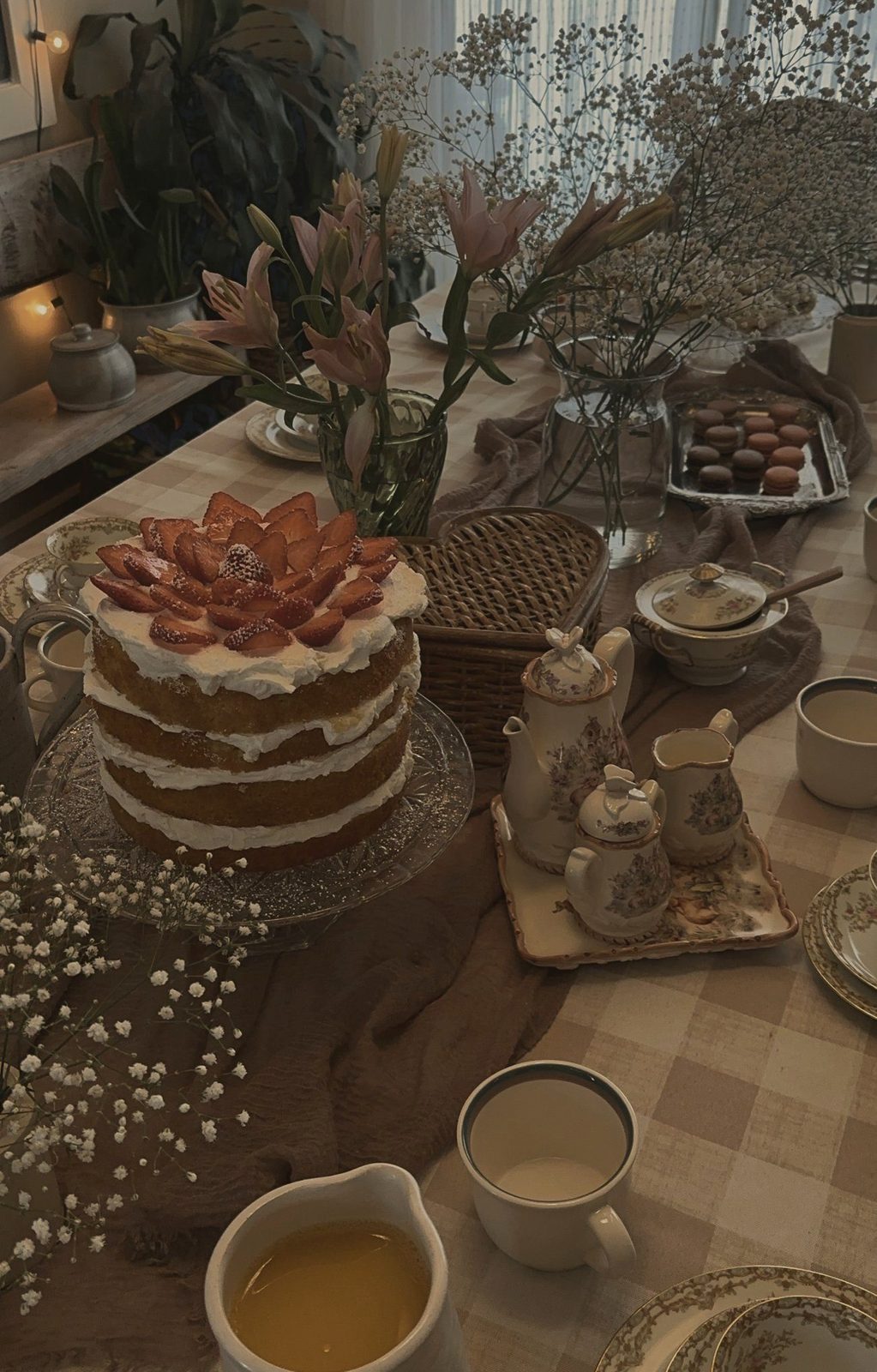 A strawberry cream cake beside a floral tea set