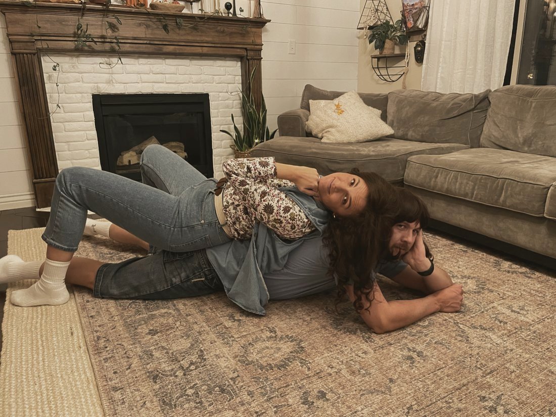 Rachel and Beau being ridiculous on the rug, him in a long wig