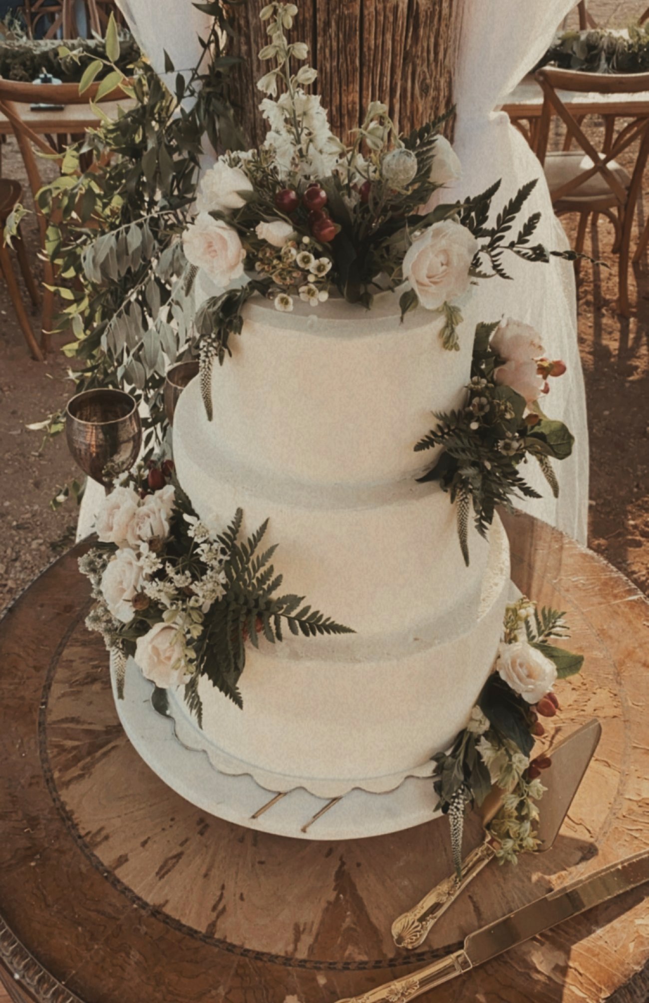 A three-tier white cake with roses and ferns