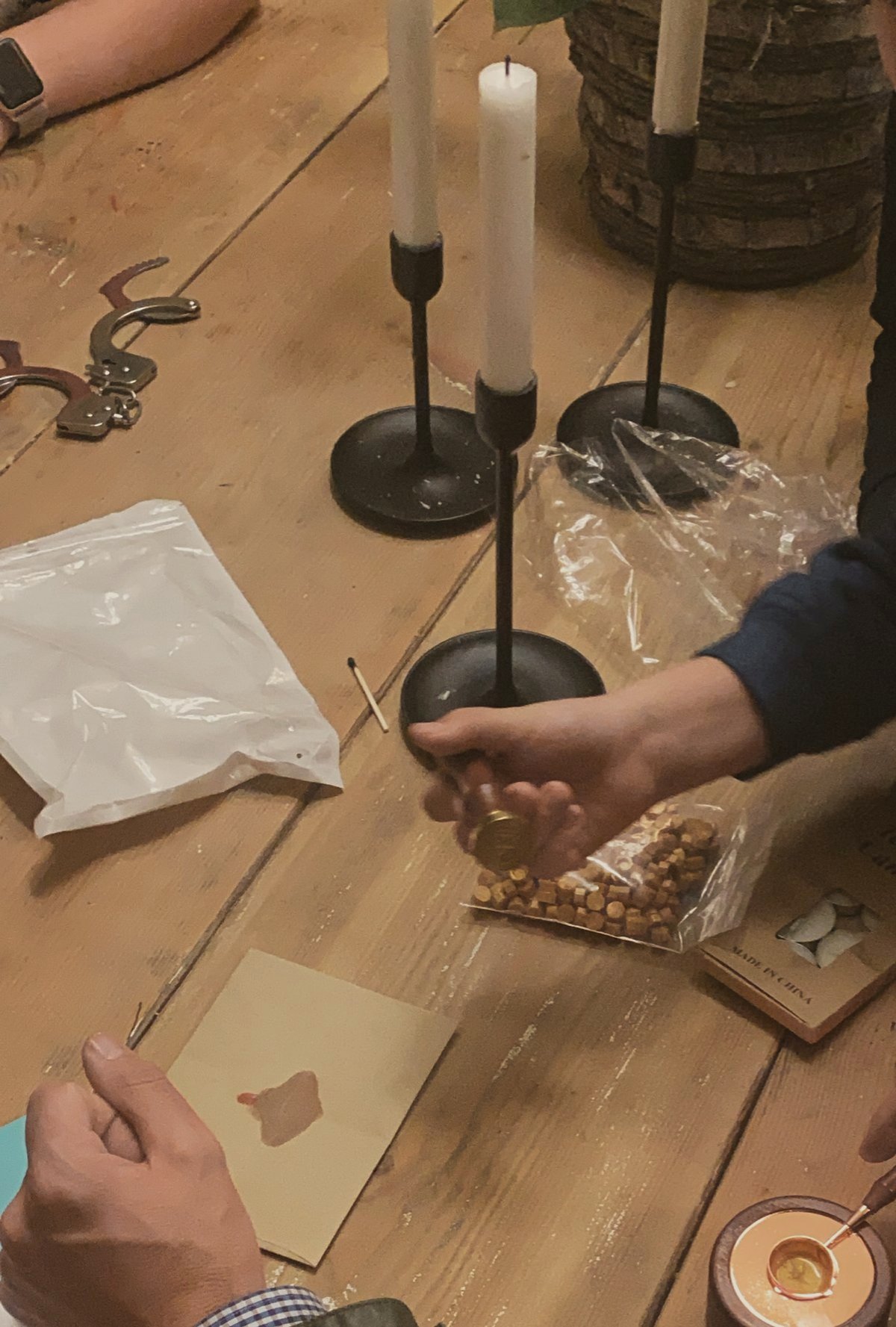 Hands melting wax for seals by black candlesticks